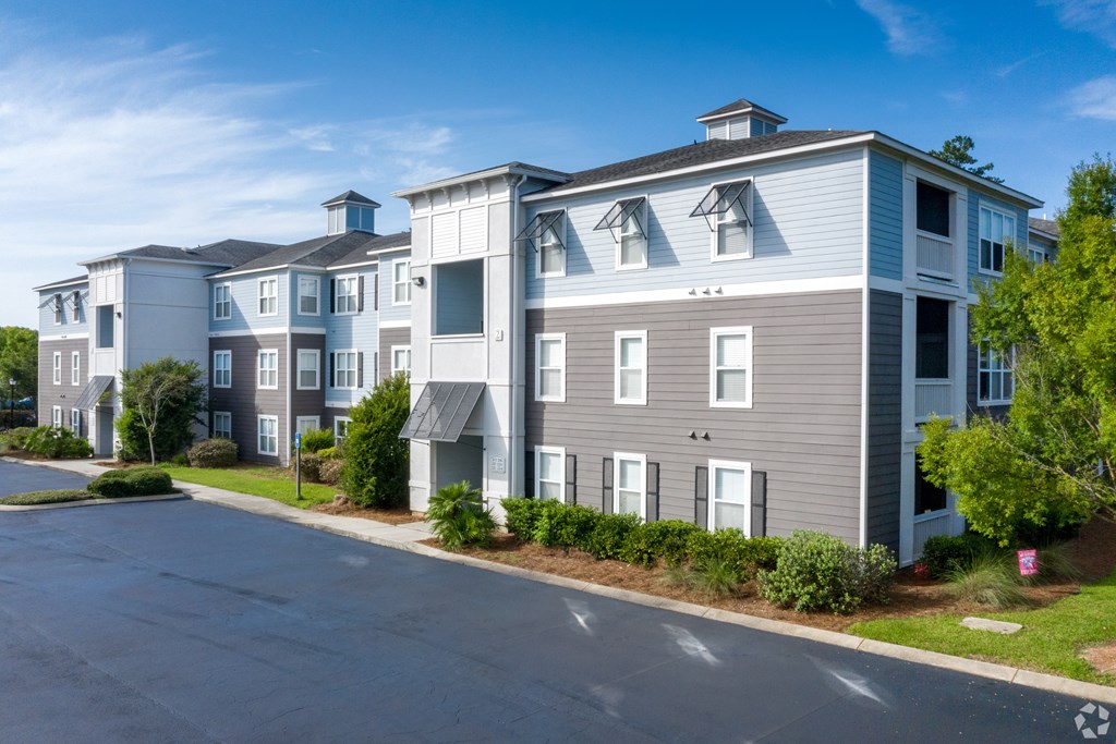 A large apartment complex with multiple buildings and a parking lot in front.