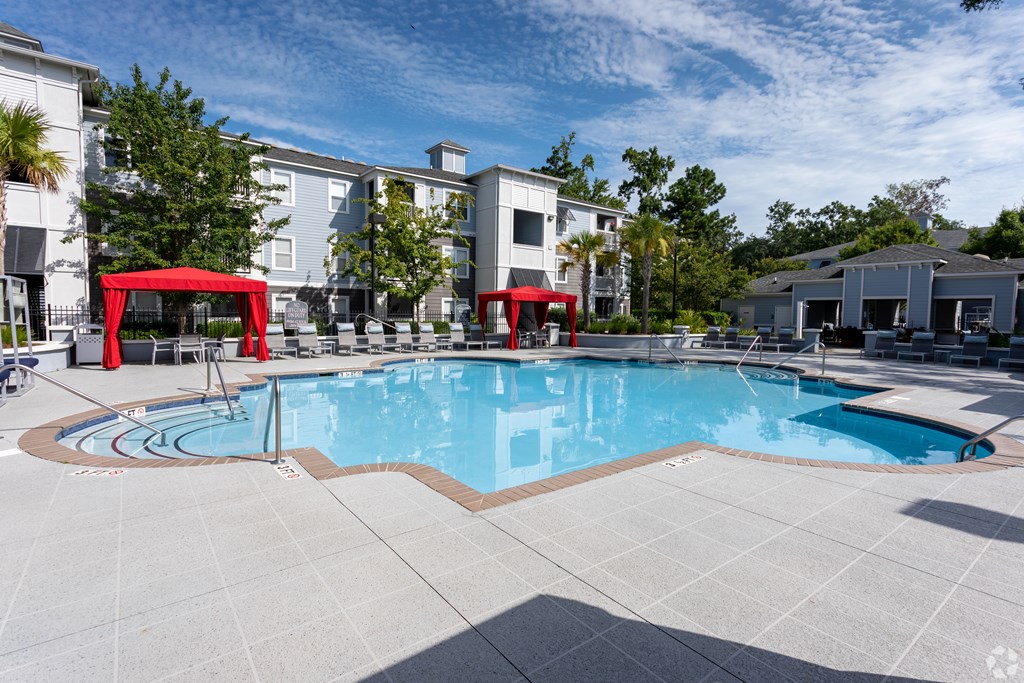 A swimming pool surrounded by a red canopy and a white building in the background.