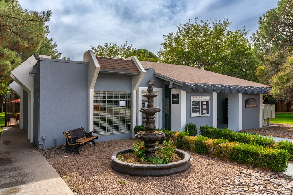 A grey building with a fountain in front of it.