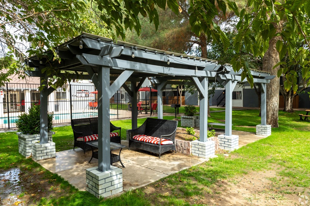 A gazebo with two red and white striped chairs sits in a grassy area.