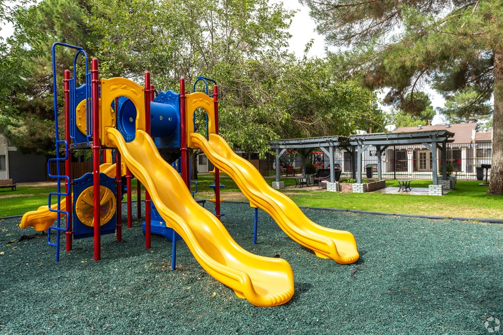 A playground with a yellow slide and a blue and red structure.