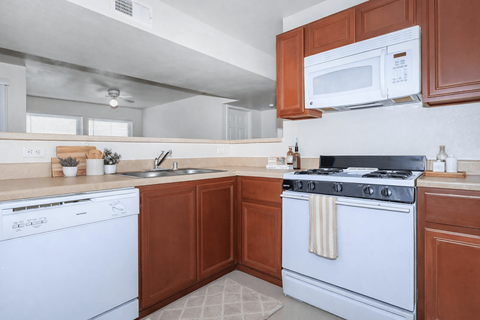 A white dishwasher is next to a white stove in a kitchen.