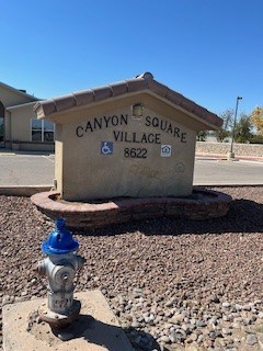 A fire hydrant is in front of a sign that says Canyon Square Village.