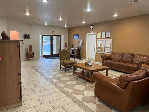 A waiting room with brown leather couches and a wooden door.
