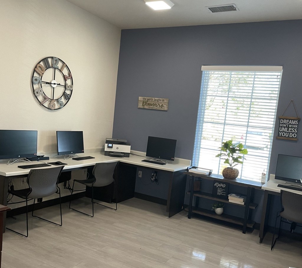 A room with a clock on the wall and a desk with a computer.