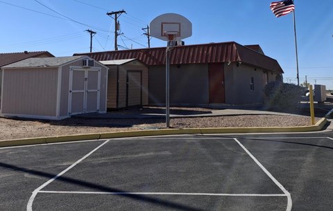 A basketball court with a basketball hoop and a portable building in the background.