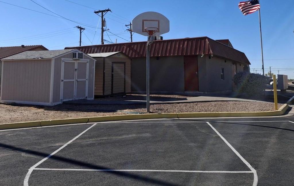 A basketball court with a basketball hoop and a portable building in the background.