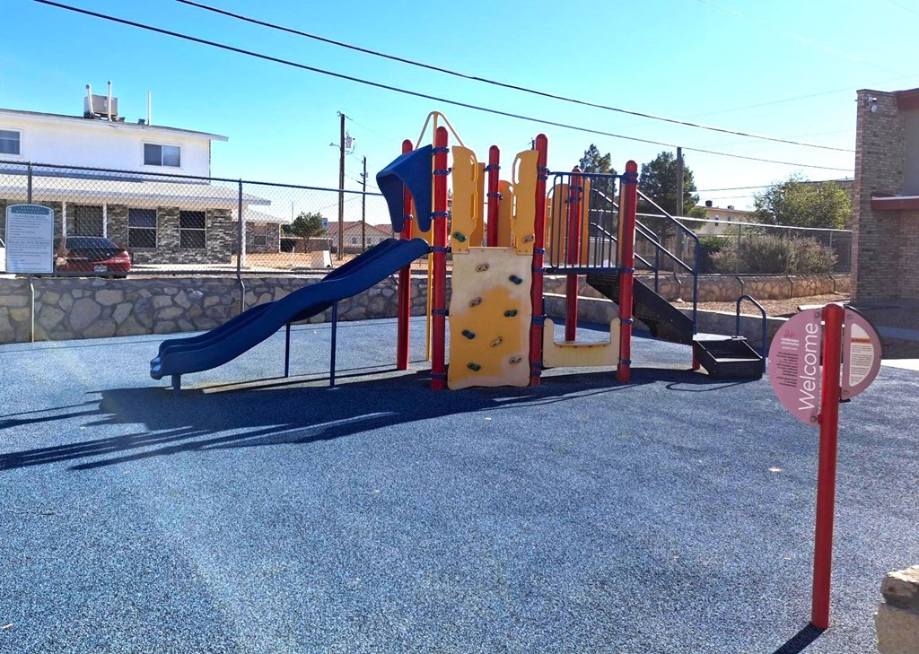 A playground with a blue slide and yellow climbing wall.
