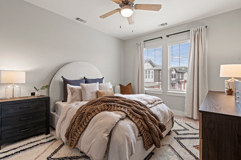 A bedroom with a large bed and a ceiling fan.