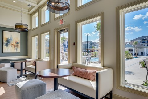 A room with a table and chairs and a window with a view of a pool and buildings outside.