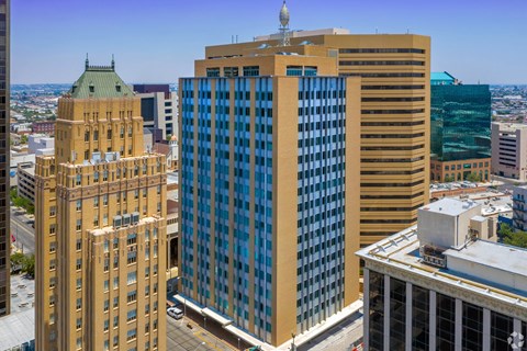 A cityscape with a large building in the foreground and a green dome building in the background.