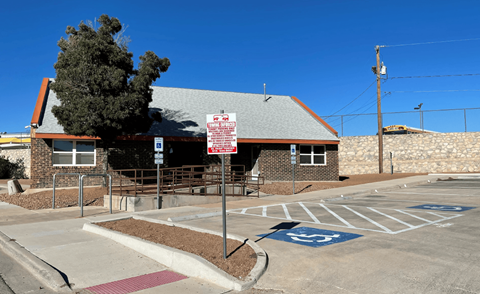 A parking lot with a building and a sign in front of it.