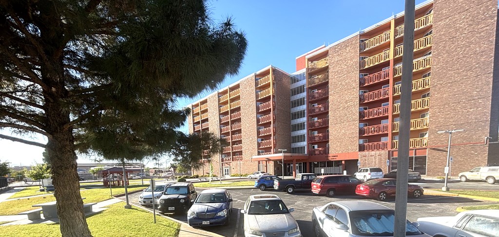 A parking lot with cars and a tall building in the background.