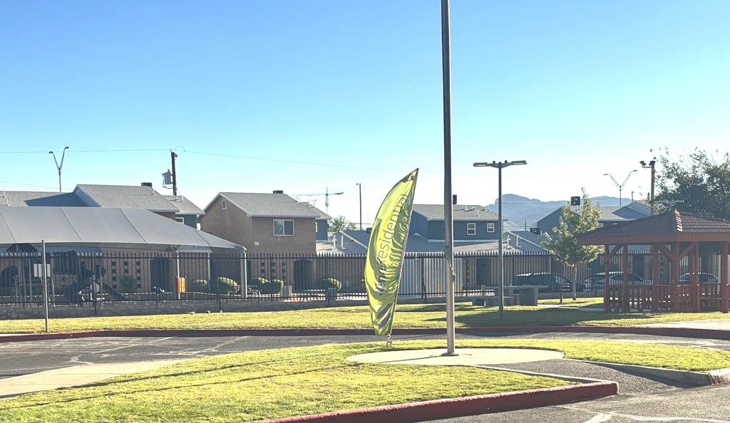 A green sign with a yellow arrow is in the middle of a grassy area.