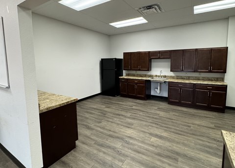 A kitchen area with brown cabinets and a black refrigerator.