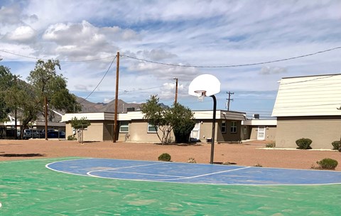 A basketball court with a basketball hoop and a building in the background.