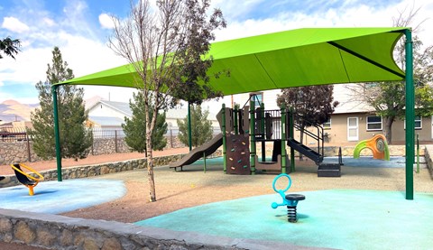 A playground with a green canopy and a slide.