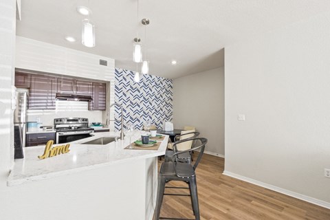 a kitchen with a white counter top and a bar with three stools