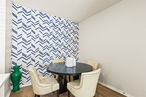 a dining room with a table and chairs and a wall with a geometric wallpaper