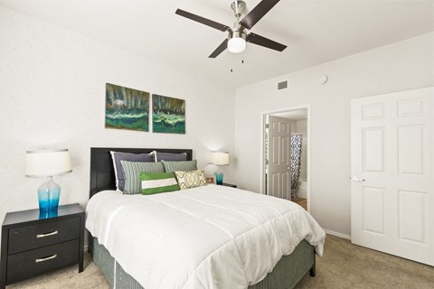 a bedroom with a white bed and a ceiling fan