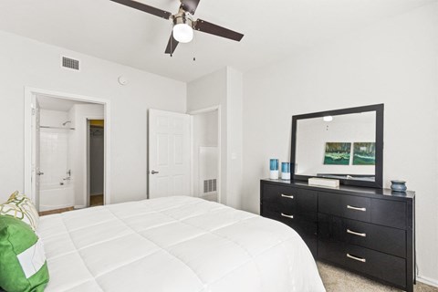a bedroom with a white bed and a ceiling fan