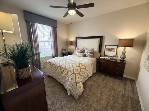 A bedroom with a bed, nightstand, and a ceiling fan.