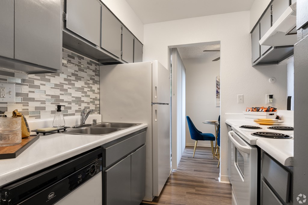 A kitchen with a black and white tile backsplash and a blue chair.