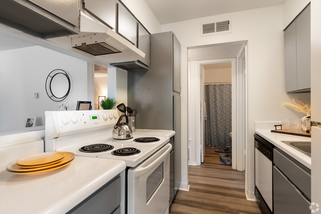 A modern kitchen with white appliances and wooden floors.