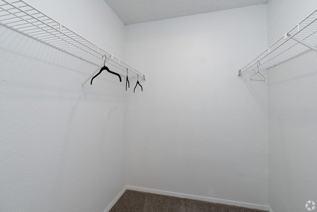 Empty white closet with clothes hangers.