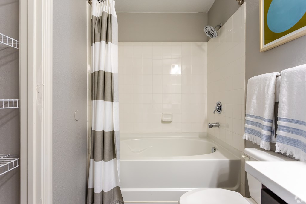 A white bathroom with a striped shower curtain.