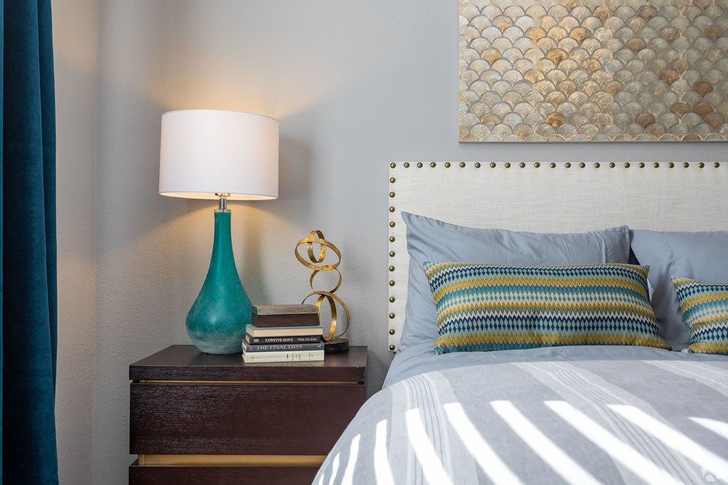 A bedroom with a white bed and a blue lamp.