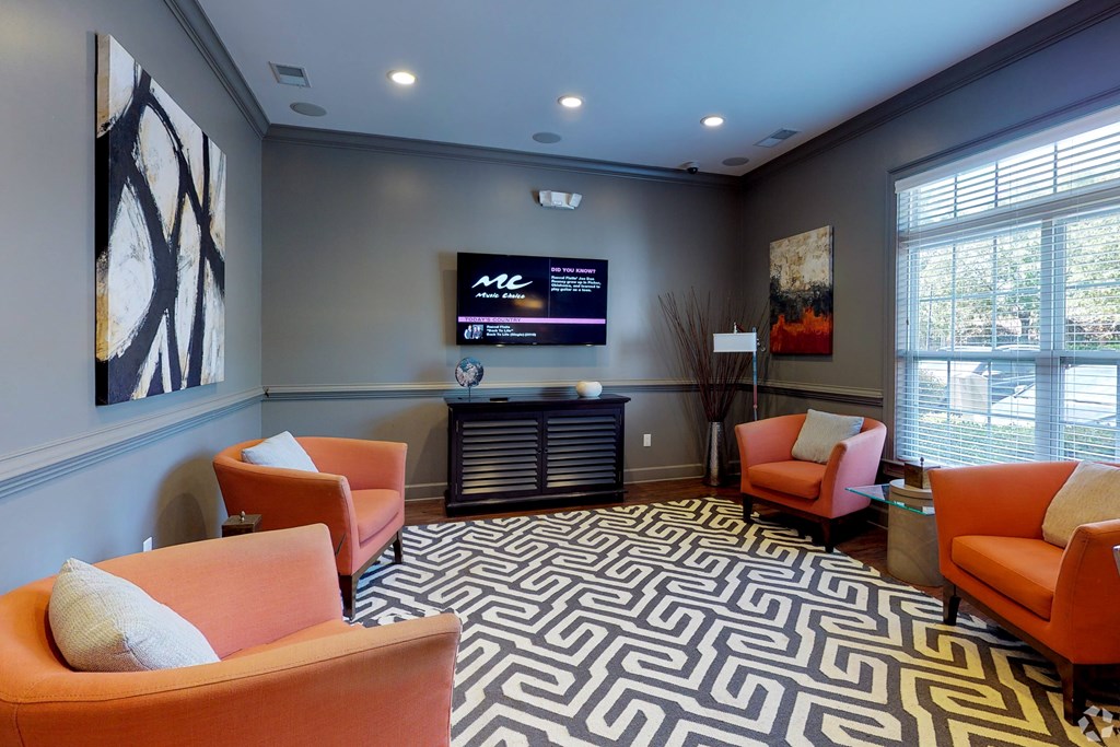 A waiting room with orange chairs and a patterned carpet.