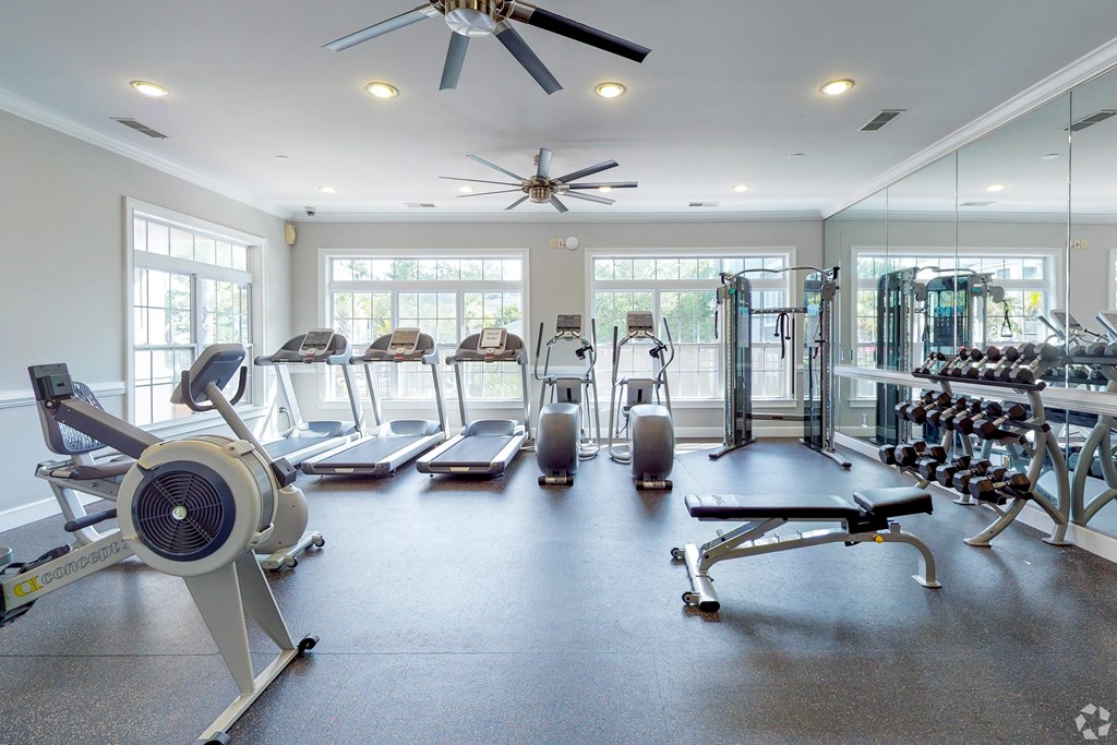 A spacious gym with a variety of equipment including treadmills, elliptical machines, and weight machines.