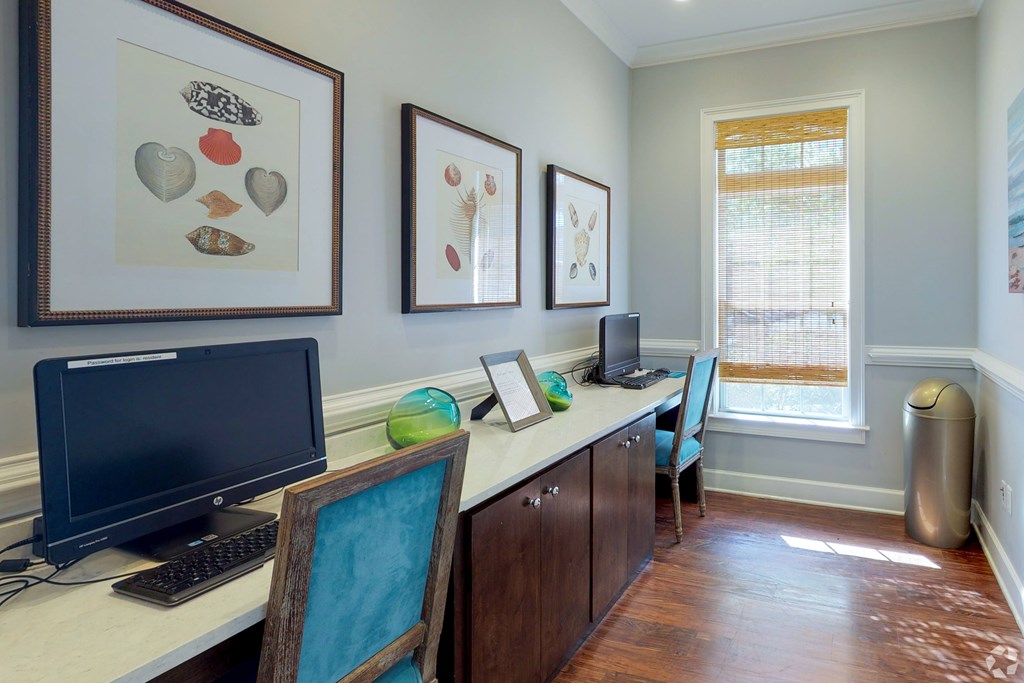 A room with a desk, chair, and two framed pictures on the wall.