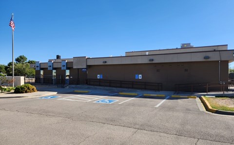 A parking lot with a building and a flag in the background.