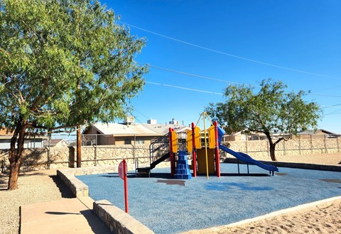 A playground with a blue water feature and a slide.