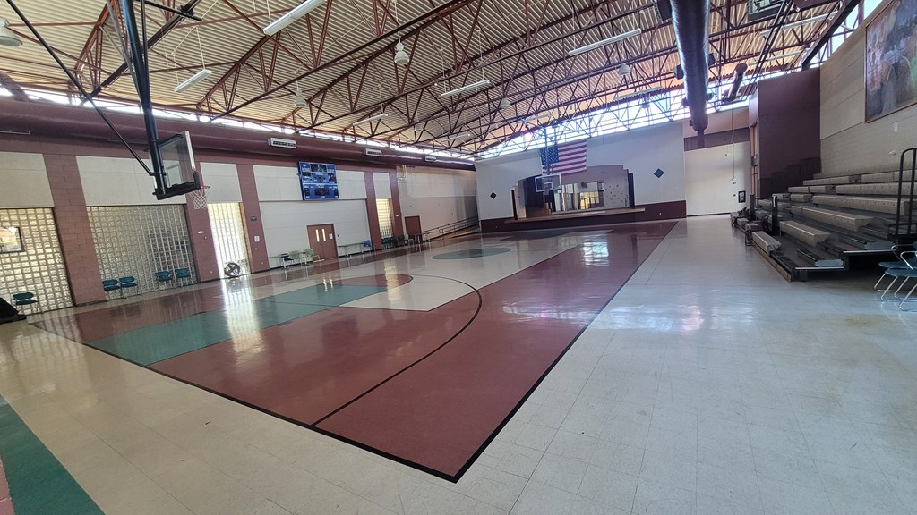 A gym with a basketball court and a basketball hoop.