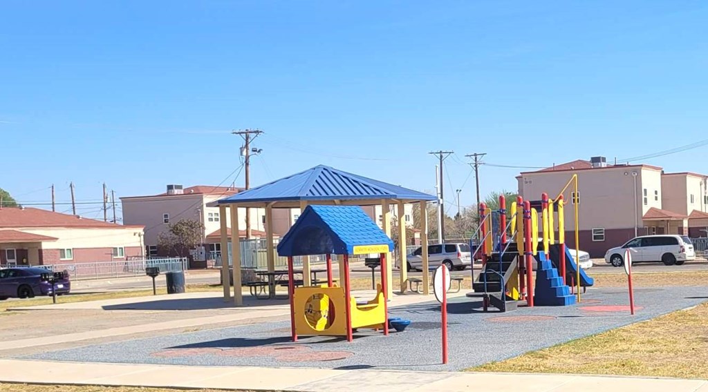 A playground with a blue canopy and a yellow slide.
