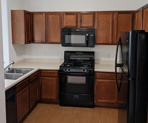 A kitchen with brown cabinets and black appliances.