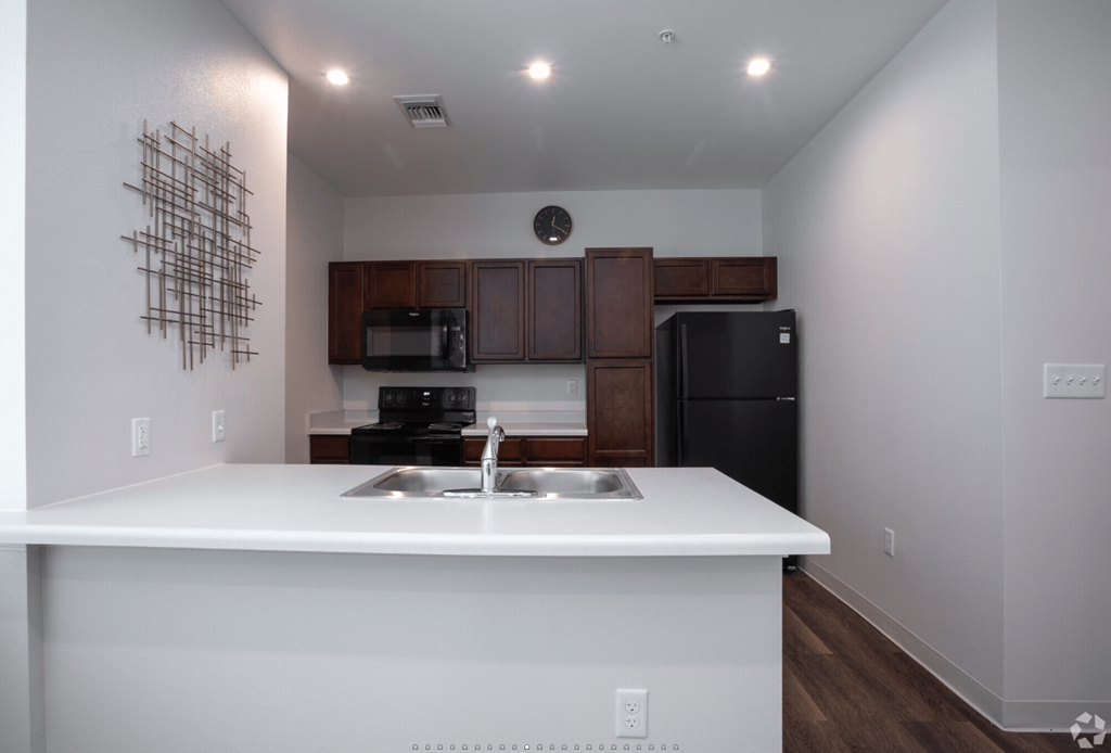 A kitchen with a white counter top and a black refrigerator.
