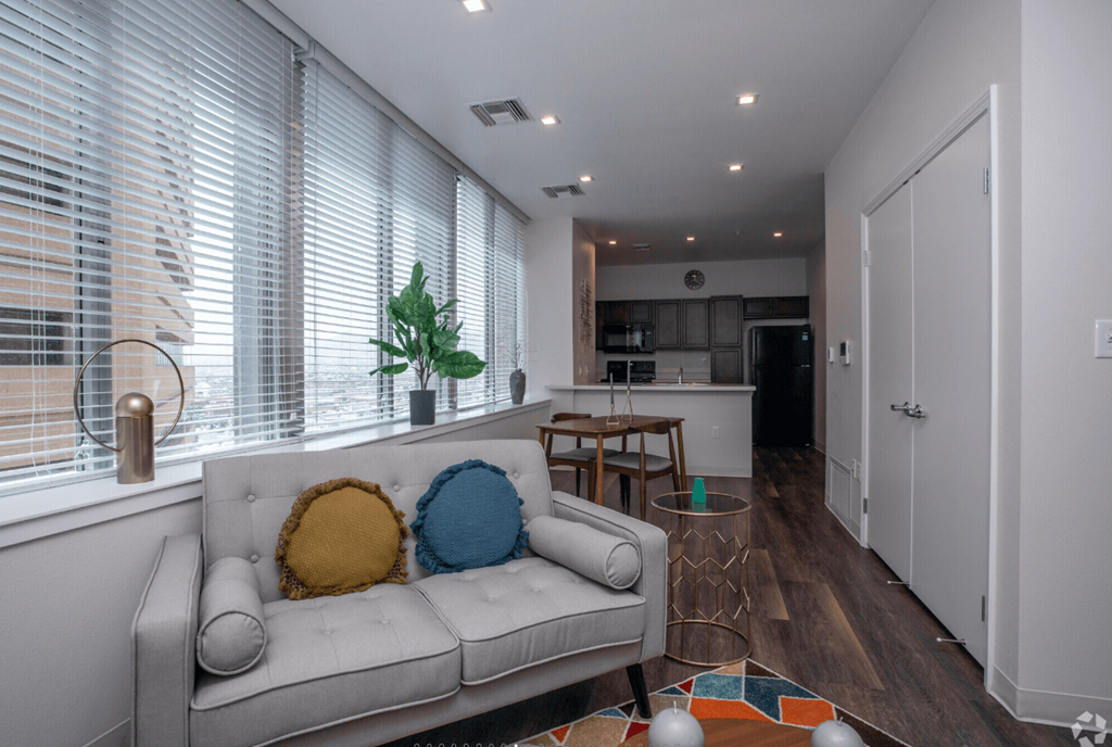 A living room with a couch, a table, and a potted plant.