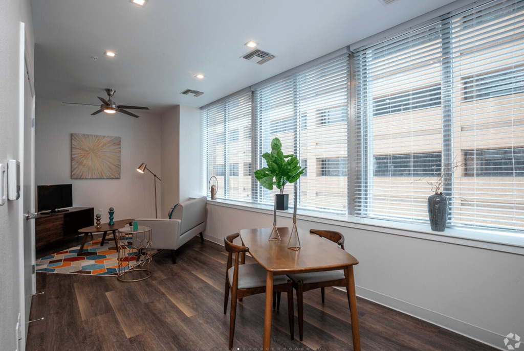A room with a table, chairs, and a plant in a vase.