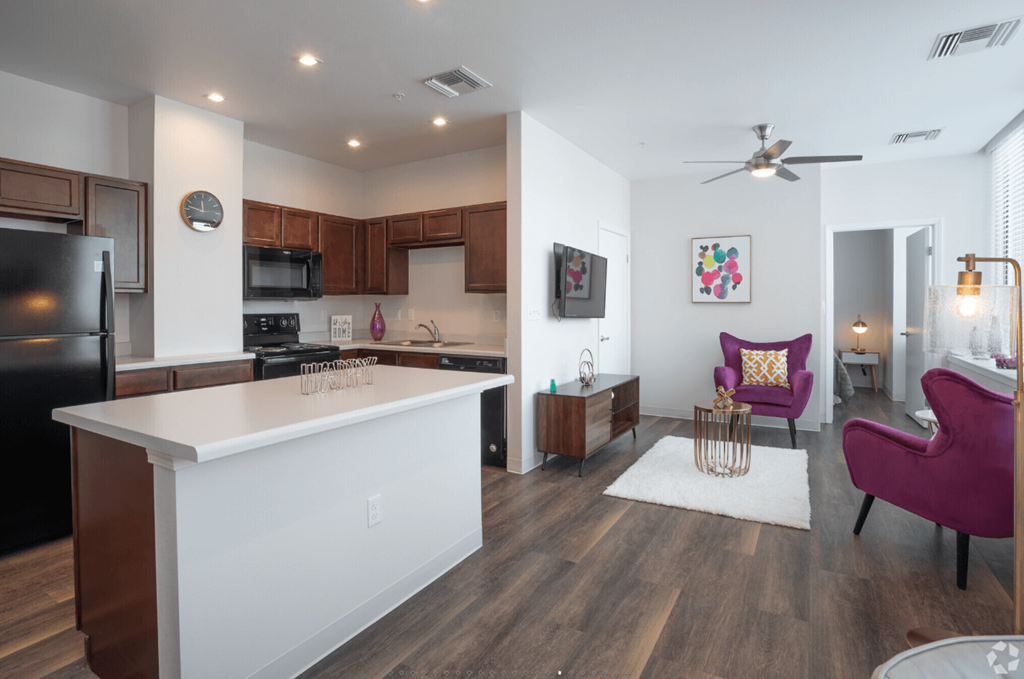 A kitchen with a white island and purple chairs.