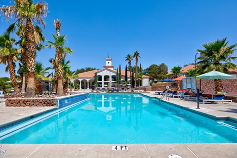 a swimming pool with palm trees and a building in the background
