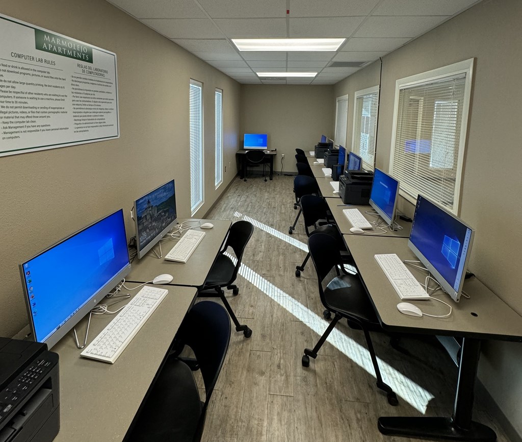 A computer lab with multiple monitors and chairs.