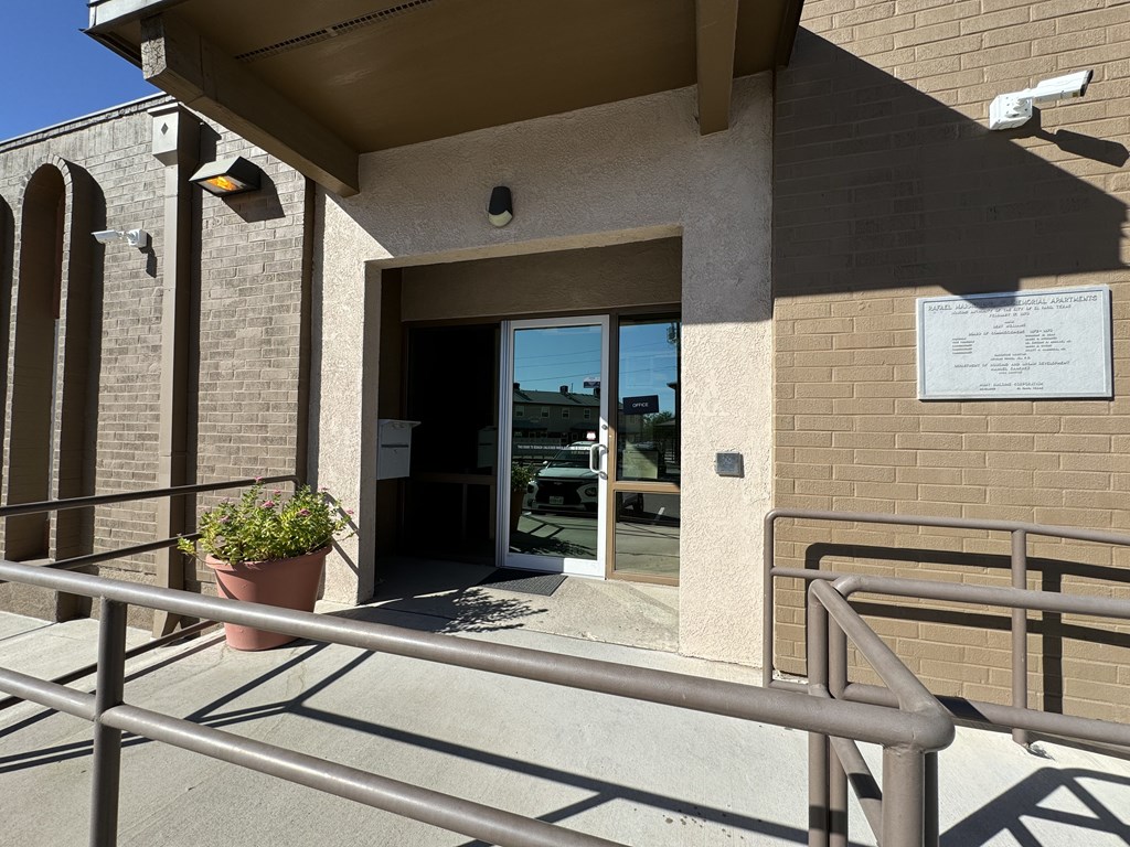 A building entrance with a sign and a potted plant.