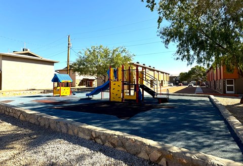 A playground with a yellow slide and a blue roofed building.