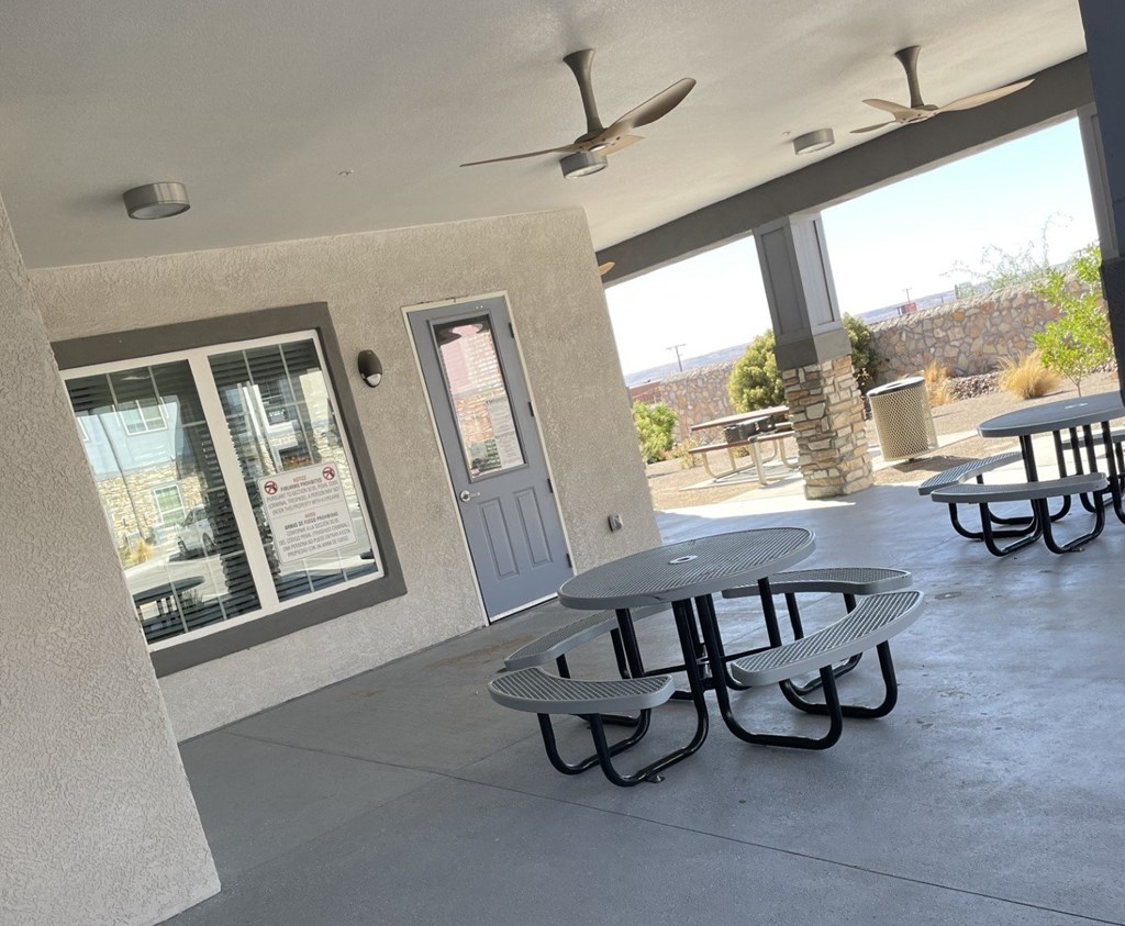 A patio with a table and chairs and a ceiling fan.