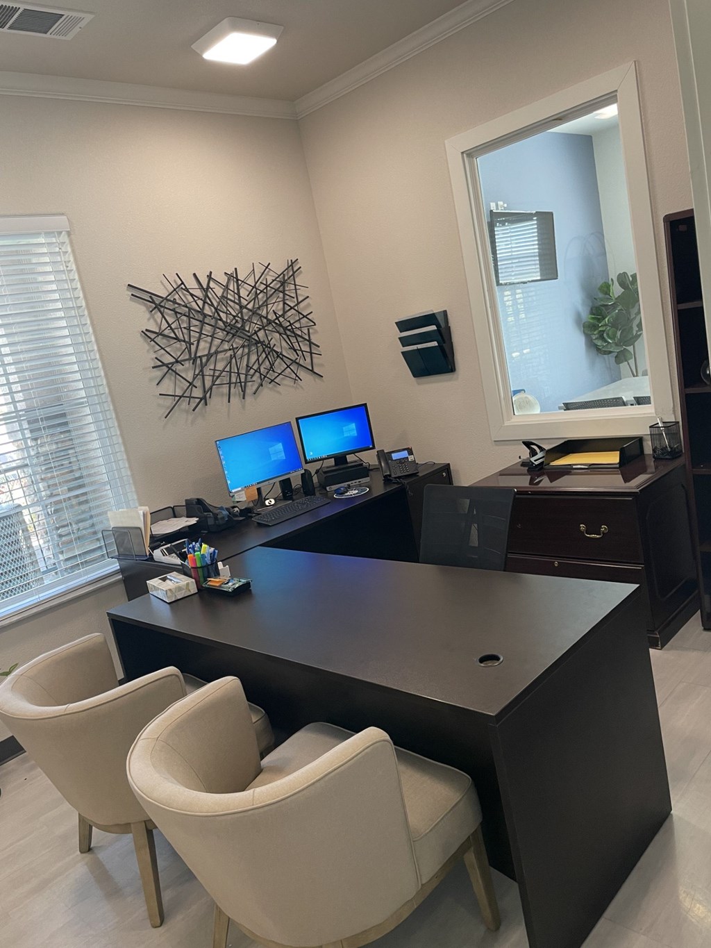 A modern office with a large desk and two chairs.