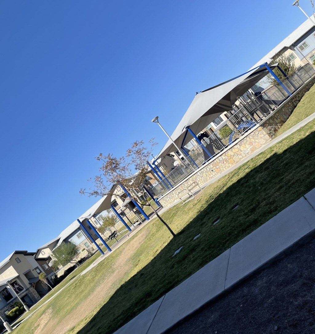 A building with a blue roof and a white wall with a tree in front of it.